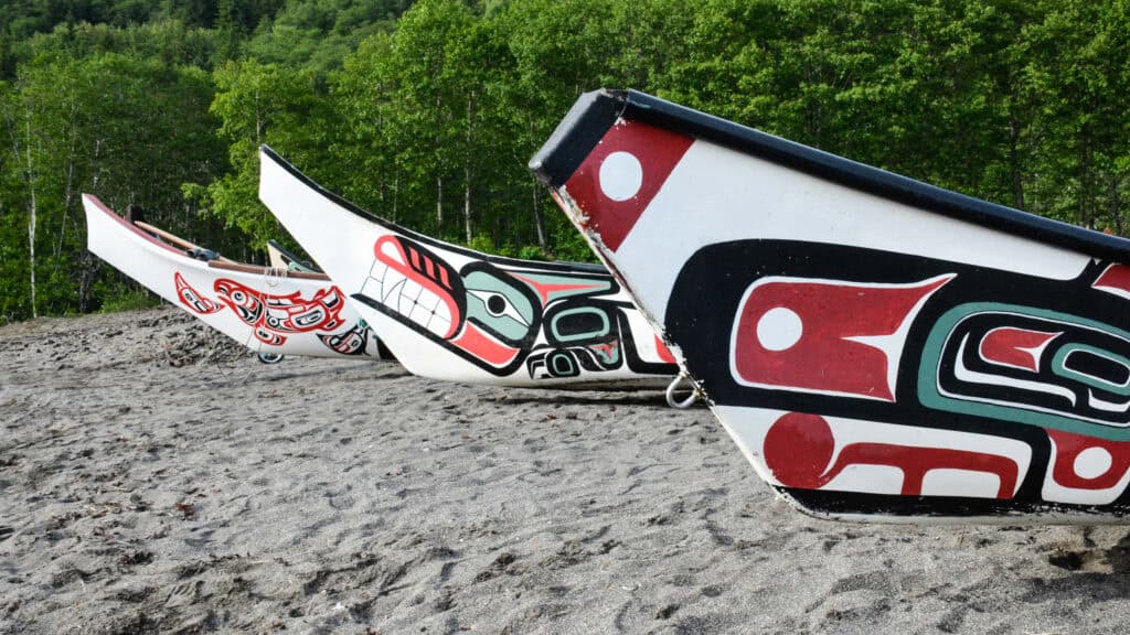 Beached canoes adorned with traditional Northwest Coast formline art.